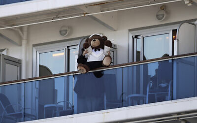 A woman holds a teddy bear on the balcony of the Diamond Princess cruise ship docked in the Yokohama Port in Yokohama, near Tokyo, February 11, 2020. (Jae C. Hong/AP)