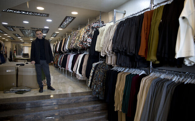 Palestinian shopkeeper Bilal Dwaik poses for a photo in his store, which sells clothes he imports from China, in the West Bank city Hebron, February 12, 2020. (Majdi Mohammed/AP) Palestinian shopkeeper Bilal Dwaik poses for a photo in his store, which sells clothes he imports from China, in the West Bank city Hebron, February 12, 2020. (Majdi Mohammed/AP)
