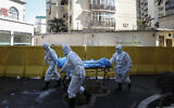 Medical workers move a person who died of COVID-19 at a hospital in Wuhan in central China's Hubei province, February 16, 2020. (Chinatopix via AP)