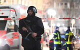 A police officer stands guard near the scene in front of a restaurant after a shooting in central Hanau, Germany, February 20, 2020. Eight people were killed in shootings in the German city of Hanau the previous evening, authorities said. (Boris Roessler/dpa via AP)