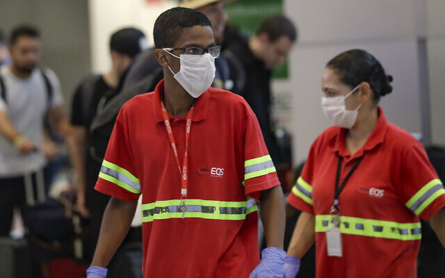 Airport employees wear masks as a precaution against the spread of the new coronavirus as they work at the Sao Paulo International Airport in Sao Paulo, Brazil, Wednesday, Feb. 26, 2020. (AP Photo/Andre Penner) Airport employees wear masks as a precaution against the spread of the new coronavirus as they work at the Sao Paulo International Airport in Sao Paulo, Brazil, Wednesday, Feb. 26, 2020. (AP Photo/Andre Penner)