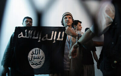 In this April 23, 2013 file photo, a suspected Yemeni al-Qaida militant, center, holds a banner as he stands behind bars during a court hearing in state security court in Sanaa, Yemen.(AP Photo/Hani Mohammed, File)