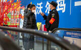 A security guard takes a customer's temperature at the entrance to a grocery store in Beijing, February 1, 2020. (AP Photo/Mark Schiefelbein)