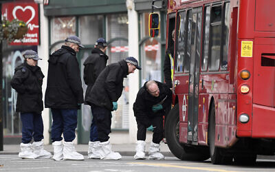 Police officers look under a bus as they work at the scene the day after a terror stabbing attack in the Streatham area of south London, February 3, 2020. (Alberto Pezzali/AP)