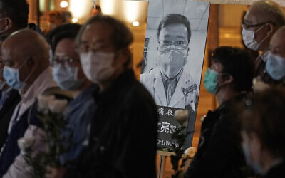 People wearing masks, attend a vigil for Chinese doctor Li Wenliang, in Hong Kong, February 7, 2020. (AP Photo/Kin Cheung)
