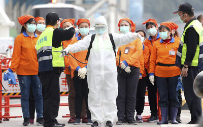 An epidemic prevention worker in a protective suit stands by to get on board the cruise ship SuperStar Aquarius docked at Keelung port in New Taipei City, Taiwan, Saturday, Feb, 8, 2020. (AP/Chiang Ying-ying)