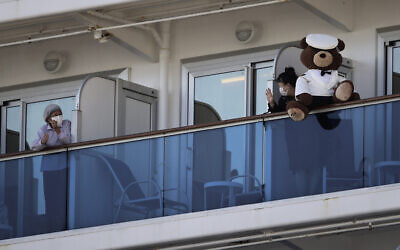 A woman with a teddy bear waves to another passenger quarantined on the Diamond Princess cruise ship in Yokohama, near Tokyo,, February 11, 2020. (AP/Jae C. Hong)