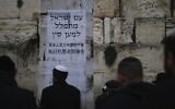 Jews pray at the Western Wall, in Jerusalem's Old City, February 16, 2020. Jewish faithful held a prayer session in search of divine intervention to help stave off the coronavirus in China. Poster in Hebrew and Chinese says, 'The People of Israel  pray for China.' (Ariel Schalit/AP)
