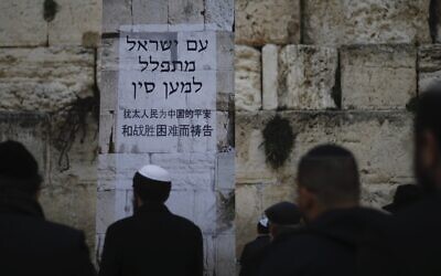 Jews pray at the Western Wall, in Jerusalem's Old City, February 16, 2020. Jewish faithful held a prayer session in search of divine intervention to help stave off the coronavirus in China. Poster in Hebrew and Chinese says, 'The People of Israel  pray for China.' (Ariel Schalit/AP)