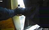 In this December 10, 2019 image made from newly released video provided by the Jersey City Police Department via the New Jersey Attorney General's Office, a Jersey City police officer fires his weapon from the window of a Catholic school during a fierce gun battle in Jersey City, New Jersey. (AP Photo/Jersey City Police Department via the New Jersey Attorney General's Office)