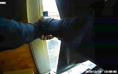 In this December 10, 2019 image made from newly released video provided by the Jersey City Police Department via the New Jersey Attorney General's Office, a Jersey City police officer fires his weapon from the window of a Catholic school during a fierce gun battle in Jersey City, New Jersey. (AP Photo/Jersey City Police Department via the New Jersey Attorney General's Office)