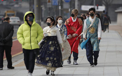 Visitors wearing face masks walk near the Gwanghwamun, the main gate of the 14th-century Gyeongbok Palace, and one of South Korea's well-known landmarks, in Seoul, South Korea, February 22, 2020.  (Lee Jin-man/AP)