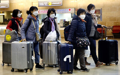 Tourists from Korea wearing protective masks walking with their belongings while waiting for a flight back to South Korea at Ben Gurion airport near Tel Aviv, February 24, 2020. (AP Photo/Ariel Schalit)