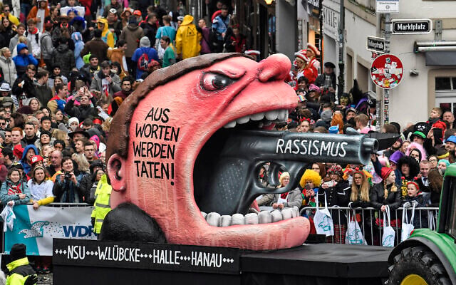 A carnival float depicts a racist with a gun in his mouth , reading 'from words to action' during the traditional carnival parade in Duesseldorf, Germany, on February 24, 2020. (Martin Meissner/AP) A carnival float depicts a racist with a gun in his mouth , reading 'from words to action' during the traditional carnival parade in Duesseldorf, Germany, on February 24, 2020. (Martin Meissner/AP)