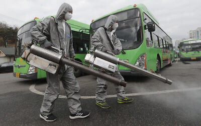 Workers wearing protective suits spray disinfectant as a precaution against the coronavirus at a bus garage in Seoul, South Korea,, February 26, 2020. (AP Photo/Ahn Young-joon)