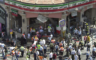 Police and medics surround the scene of a suicide bombing inside Jerusalem's Sbarro restaurant, Thursday, August 9, 2001. Fifteen people were killed, and 130 injured. A sixteenth victim died in 2023. (AP/Peter Dejong)