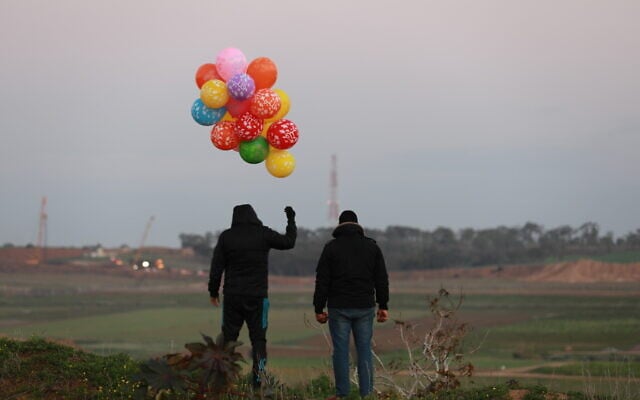 Palestinian men prepare an incendiary device to be flown toward Israel, near the Israel-Gaza border east of Al-Bureij refugee camp in the central Gaza Strip, January 22, 2020. (Ali Ahmed/Flash90)