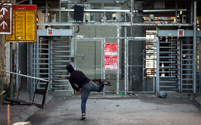 Illustrative: Palestinians throw rocks at an Israeli checkpoint during clashes in the West Bank city of Hebron on February 5, 2020. (Wisam Hashlamoun/Flash90)