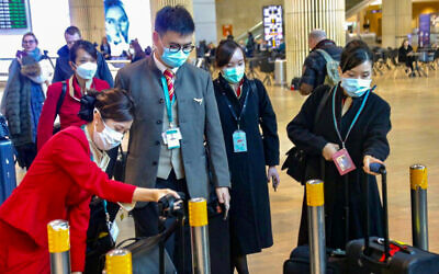 People wear face masks at Ben Gurion Airport following reports about the deadly coronavirus, February 17, 2020. (Avshalom Shoshani/Flash90)