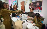 An IDF lone soldier hands a tailor a pair of trousers during an annual 'Errands Day' event in Tel Aviv on February 13, 2020. (Shahar Azran/Nefesh B'Nefesh)