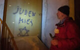 Illustrative: Italian Aldo Rolfi stands in front of the door to his home, where the writing ‘’Juden Hier,’’ German for ‘’Jews Here,’’ with a Star of David, was painted, during a torchlit protest against anti-Semitism, in Mondovi, northern Italy, January 24, 2020. (Marco Alpozzi/LaPresse via AP)