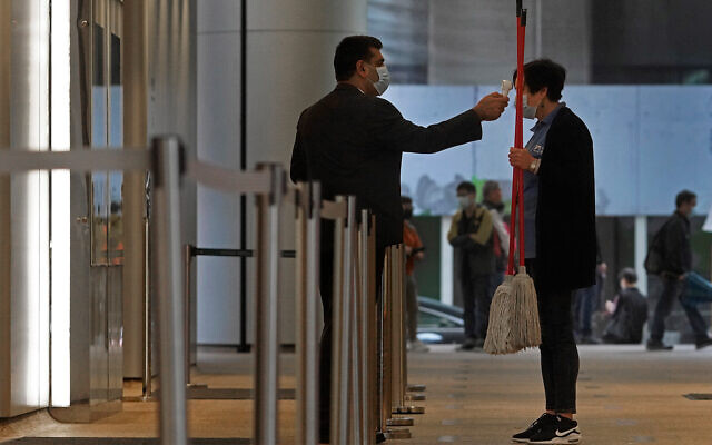 A security guard wearing a protective face mask checks the temperature of a cleaning woman amid coronavirus fears in Hong Kong, Feb. 14, 2020. (AP Photo/Vincent Yu) A security guard wearing a protective face mask checks the temperature of a cleaning woman amid coronavirus fears in Hong Kong, Feb. 14, 2020. (AP Photo/Vincent Yu)