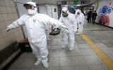 Workers wearing protective gears help clean each other's suits after disinfecting against the coronavirus at a subway station in Seoul, South Korea, February 21, 2020. (AP Photo/Ahn Young-joon)