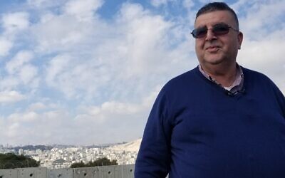 Mayor Ahmad Abu Hilal standing on a building next to the security barrier in Abu Dis on February 3, 2020. (Adam Rasgon/Times of Israel)