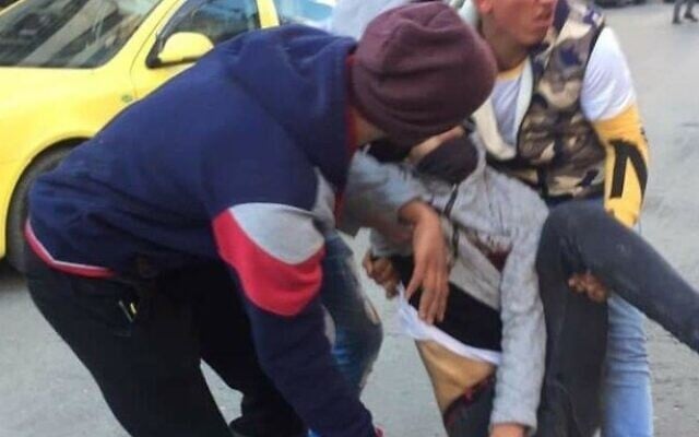 Two Palestinians drag a teenager from the scene of a clash after he was shot by IDF troops in Hebron on February 5, 2020. (Courtesy) Two Palestinians drag a teenager from the scene of a clash after he was shot by IDF troops in Hebron on February 5, 2020. (Courtesy)