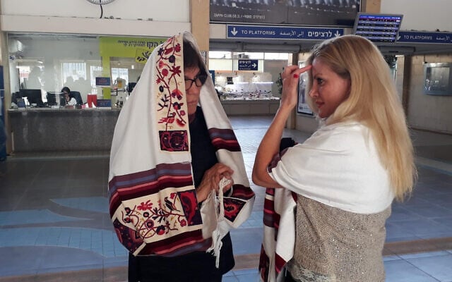 A Women of the Wall member helps a woman lay tefillin at Tel Aviv's Savidor train terminal, February 17, 2020. (Courtesy Women of the Wall) A Women of the Wall member helps a woman lay tefillin at Tel Aviv's Savidor train terminal, February 17, 2020. (Courtesy Women of the Wall)
