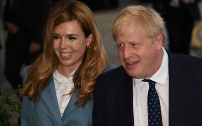 In this photo taken on September 28, 2019, Britain's Prime Minister Boris Johnson (R) walks with his partner Carrie Symonds at The Midland, near the Manchester Central convention complex in Manchester, northwest England, on the eve of the annual Conservative Party conference. (Photo by Oli SCARFF / AFP)