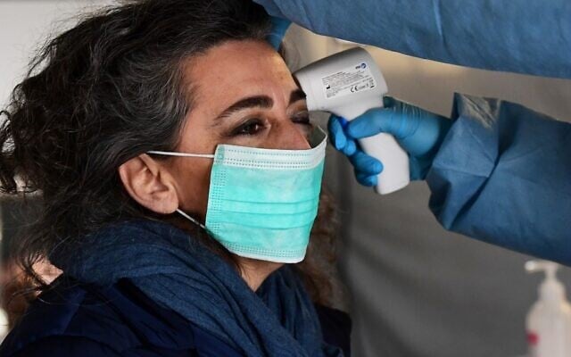 A nurse controls the temperature of a woman in the a pre-triage medical tent in front of the Cremona hospital, in Cremona, northern Italy, on March 4, 2020 (Miguel MEDINA / AFP)