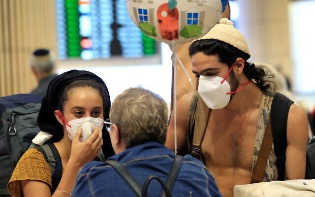 A young couple wearing protective masks are greeted upon arrival at Ben Gurion airport in Israel on March 4, 2020. (Emmanuel DUNAND / AFP) A young couple wearing protective masks are greeted upon arrival at Ben Gurion airport in Israel on March 4, 2020. (Emmanuel DUNAND / AFP)