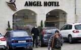 Palestinian men, one of them wearing a protective mask, walk out of the Angel Hotel hotel in the West Bank city of Bethlehem on March 6, 2020. (Musa Al Shaer/AFP)