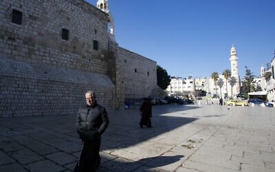 A priest walks in the Church of the Nativity compound in the West Bank city of Bethlehem on March 8, 2020, after it came under lockdown two days ago as an emergency measure to limit the spread of the novel coronavirus. (Musa Al SHAER / AFP)