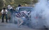 Palestinian youths take cover amidst tear gas smoke during clashes with Israeli forces in a village south of Nablus in the West Bank on March 11, 2020. (JAAFAR ASHTIYEH / AFP)
