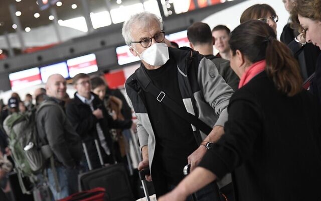 Travelers with protective face masks wait in a check-in line at Paris-Charles-de-Gaulle airport after a US 30-day ban on travel from Europe due to the COVID-19 spread in Roissy-en-France on March 12, 2020. (Bertrand GUAY / AFP) Travelers with protective face masks wait in a check-in line at Paris-Charles-de-Gaulle airport after a US 30-day ban on travel from Europe due to the COVID-19 spread in Roissy-en-France on March 12, 2020. (Bertrand GUAY / AFP)