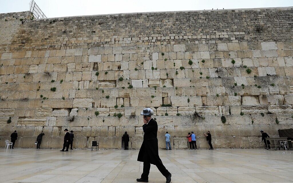An ultra-Orthodox Jewish man wearing a plastic-covered hat speaks on the phone at the nearly deserted Western Wall in Jerusalem's Old City on March 12, 2020, after Israel announced new restrictions to contain the coronavirus. (Emmanuel Dunand/AFP)