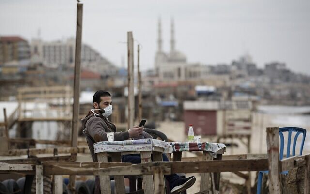 A Palestinian man wearing a mask as a means of protection against the coronavirus COVID-19, sits on the seashore in Gaza City on March 13, 2020. (Mohammed Abed/AFP) A Palestinian man wearing a mask as a means of protection against the coronavirus COVID-19, sits on the seashore in Gaza City on March 13, 2020. (Mohammed Abed/AFP)