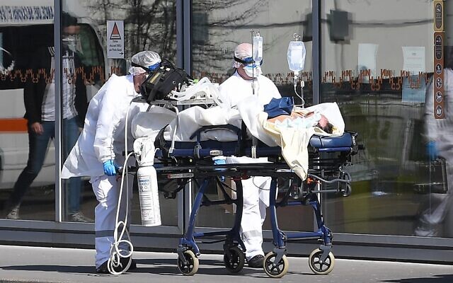 A patient under respiratory assistance is escorted to the Strasbourg University Hospital by members of the medical staff of the SAMU-SMUR emergency services who wear protective suits and facemasks, in Strasbourg, on March 16, 2020, during a COVID-19 outbreak hitting Europe. (Patrick HERTZOG / AFP) A patient under respiratory assistance is escorted to the Strasbourg University Hospital by members of the medical staff of the SAMU-SMUR emergency services who wear protective suits and facemasks, in Strasbourg, on March 16, 2020, during a COVID-19 outbreak hitting Europe. (Patrick HERTZOG / AFP)