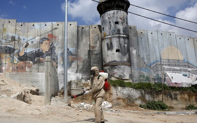 A Palestinian sanitary department worker sprays disinfectant on March 16, 2020 around the refugee camp of Aida near Bethlehem. (Musa Al SHAER / AFP) A Palestinian sanitary department worker sprays disinfectant on March 16, 2020 around the refugee camp of Aida near Bethlehem. (Musa Al SHAER / AFP)