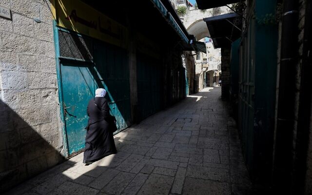 A Muslim woman makes her way past closed shops in a deserted alley, in the Old City of Jerusalem on March 16, 2020. (Emmanuel Dunand/AFP) A Muslim woman makes her way past closed shops in a deserted alley, in the Old City of Jerusalem on March 16, 2020. (Emmanuel Dunand/AFP)