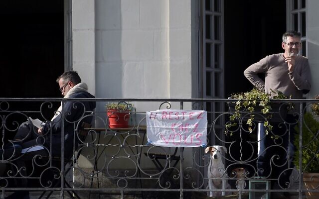 Two men stand on their balcony with a banner reading "stay at home," in Nantes, on March 17, 2020, as a strict lockdown comes into effect to stop the spread of the COVID-19 in France. (Sebastien SALOM-GOMIS / AFP) Two men stand on their balcony with a banner reading "stay at home," in Nantes, on March 17, 2020, as a strict lockdown comes into effect to stop the spread of the COVID-19 in France. (Sebastien SALOM-GOMIS / AFP)