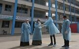 Palestinian health workers wearing  protective face masks are pictured in the courtyard of a United Nations Relief and Works Agency for Palestinian Refugees (UNRWA) school at al-Shati refugee camp in Gaza City on March 18, 2020, as preparations are underway to receive, examine and isolate victims of the COVID-19 coronavirus. (MAHMUD HAMS / AFP)
