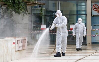 An Israeli firefighter sprays disinfectant at the entrance of Ichilov Hospital in Tel Aviv on March 20, 2020. (Jack Guez/AFP)