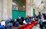 Palestinian Muslims gather to perform their Friday prayers in front of the the closed doors of Al-Aqsa mosque in Jerusalem's Old City, after clerics shut the doors of the mosque and the Dome of the Rock, in a bid to stem the spread of the novel coronavirus, on March 20, 2020. (AHMAD GHARABLI / AFP)