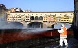 An employee of the municipal company disinfects a street by the Ponte Vecchio, in Florence, on March, 21 2020, as part of the measures taken by Italian government to fight against the spread of the COVID-19, the novel coronavirus. (Carlo BRESSAN / AFP)