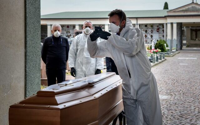 Illustrative: A pallbearer takes a picture of a coffin for the relatives of a deceased person at the cemetery of Grassobbio in the province of Bergamo, as they could not attend the ceremony because they are in quarantine as a result of the novel coronavirus, March 23, 2020 . (Piero Cruciatti/AFP) Illustrative: A pallbearer takes a picture of a coffin for the relatives of a deceased person at the cemetery of Grassobbio in the province of Bergamo, as they could not attend the ceremony because they are in quarantine as a result of the novel coronavirus, March 23, 2020 . (Piero Cruciatti/AFP)