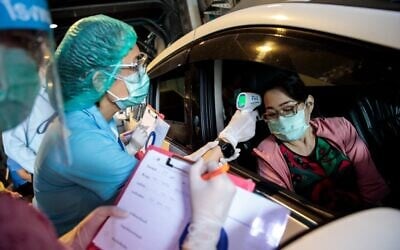 Medical staff dressed in protective gear test a woman for the COVID-19 novel coronavirus at a drive-through testing centre at Vibhavadi Hospital in Bangkok on March 25, 2020. (Jack Taylor/AFP)