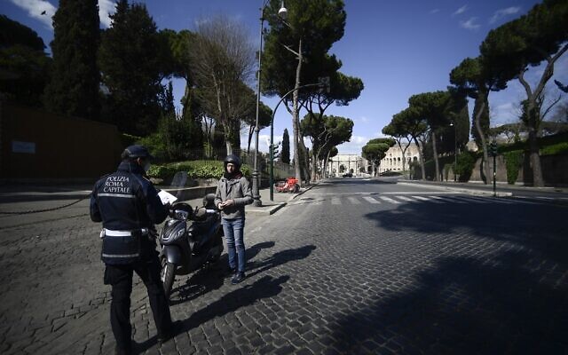 A police officer (L) stops a scooter rider to check traveling permits on a deserted road in central Rome during the country's lockdown following the COVID-19 new coronavirus pandemic, March 25, 2020 . (Filippo MONTEFORTE/AFP) A police officer (L) stops a scooter rider to check traveling permits on a deserted road in central Rome during the country's lockdown following the COVID-19 new coronavirus pandemic, March 25, 2020 . (Filippo MONTEFORTE/AFP)
